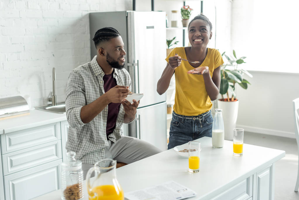 african american couple eating cornflakes with milk at kitchen - Photo, Image