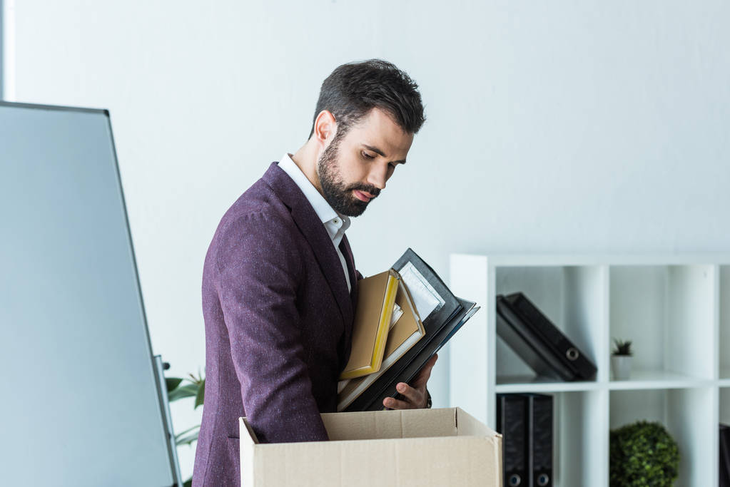 fired young businessman putting books and folders into box - Photo, Image