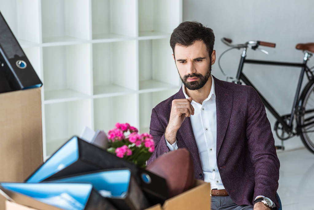ontslagen jonge zakenman zitten in kantoor en systeemkast van persoonlijke spullen - Foto, afbeelding