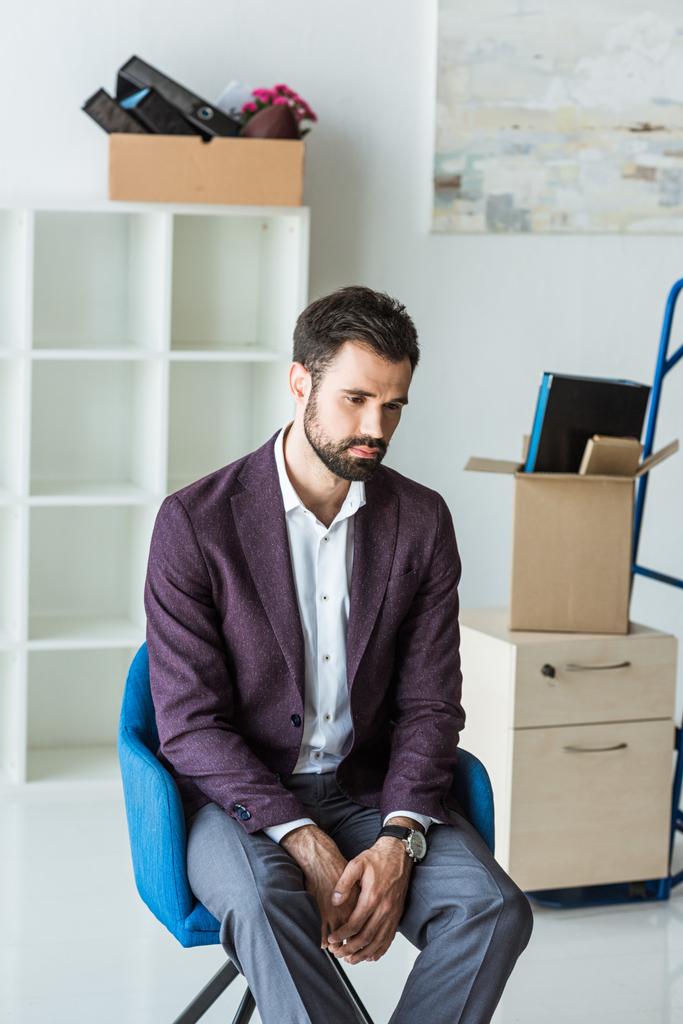 depressief ontslagen zakenman zittend op een stoel in lege kantoor - Foto, afbeelding
