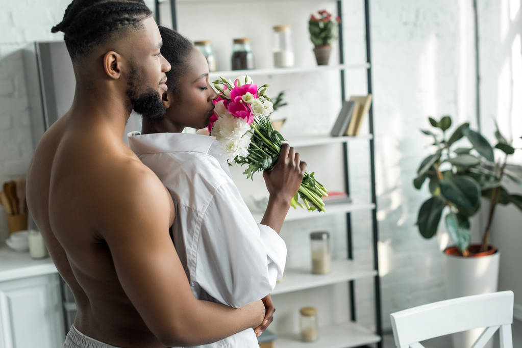africano americano fidanzato abbracciare fidanzata e lei annusare mazzo di fiori a cucina
 - Foto, immagini