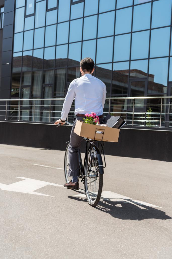 rear view of manager riding on bicycle with box on trunk - Photo, Image