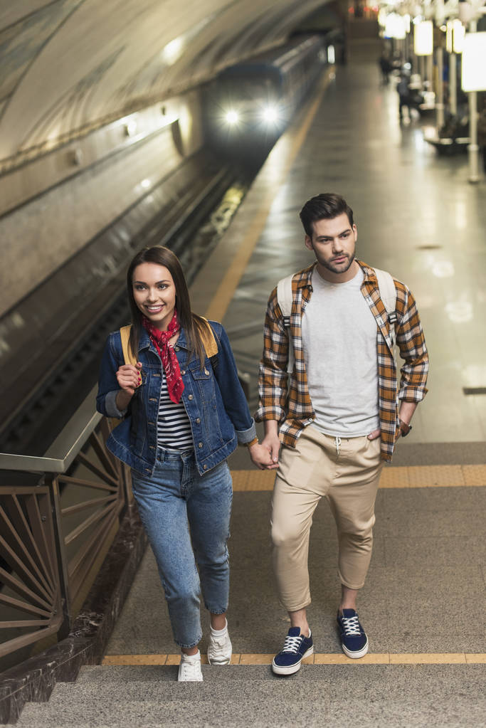 地下鉄駅構内でバックパックとスタイリッシュな観光客のカップル - 写真・画像