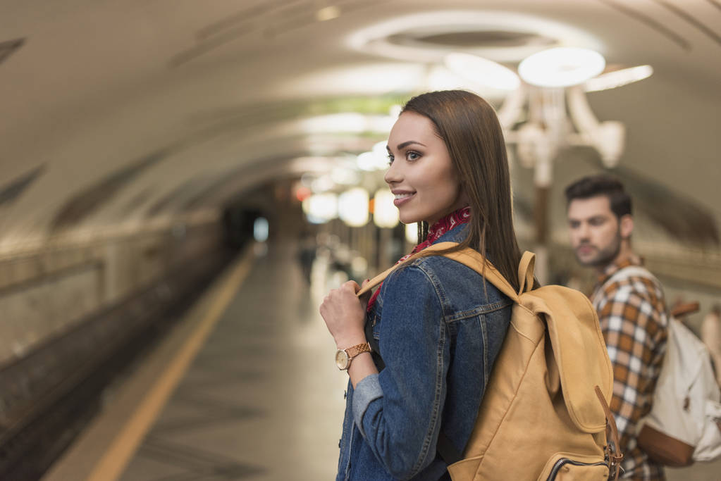 hymyilevä nuori naispuolinen matkustaja poikaystävänsä kanssa metroasemalla
  - Valokuva, kuva