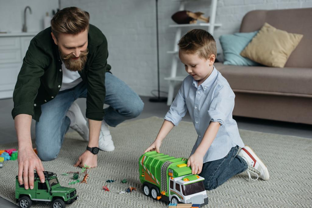 pai e filho brincando com carros de brinquedo juntos no chão em casa
 - Foto, Imagem