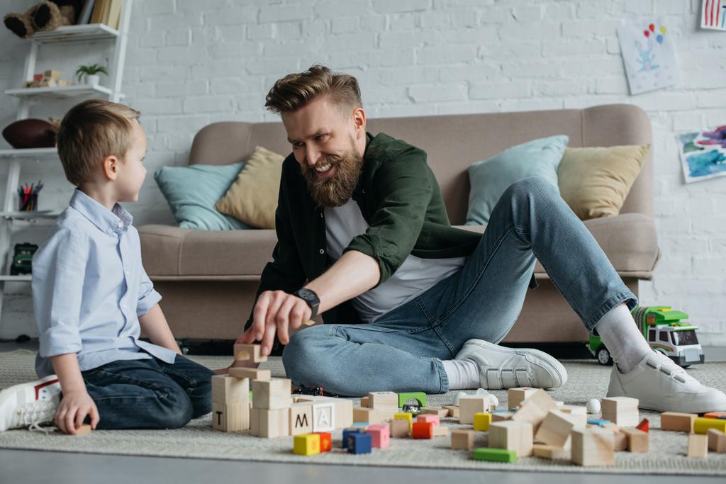 щасливий батько і син грають з дерев'яними блоками вдома
 - Фото, зображення