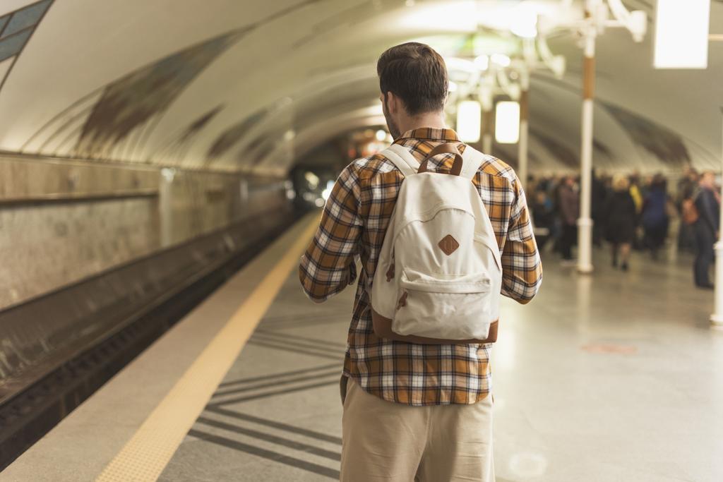 Achteraanzicht van stijlvolle man met rugzak op metrostation  - Foto, afbeelding