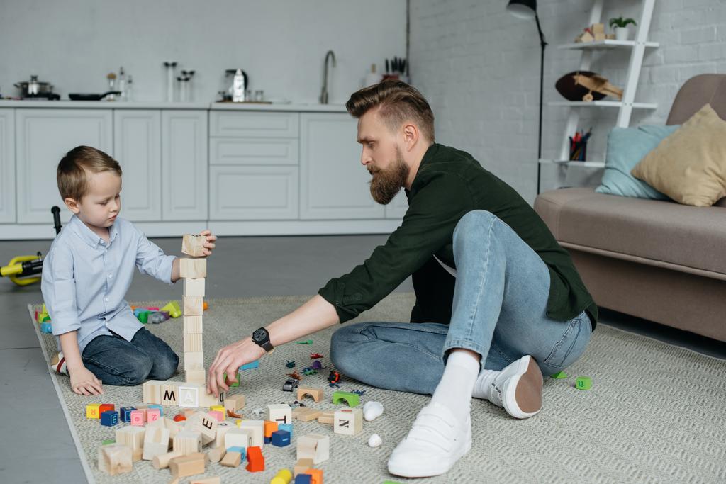 Ojciec i syn bawić się klockami drewnianymi razem w domu - Zdjęcie, obraz