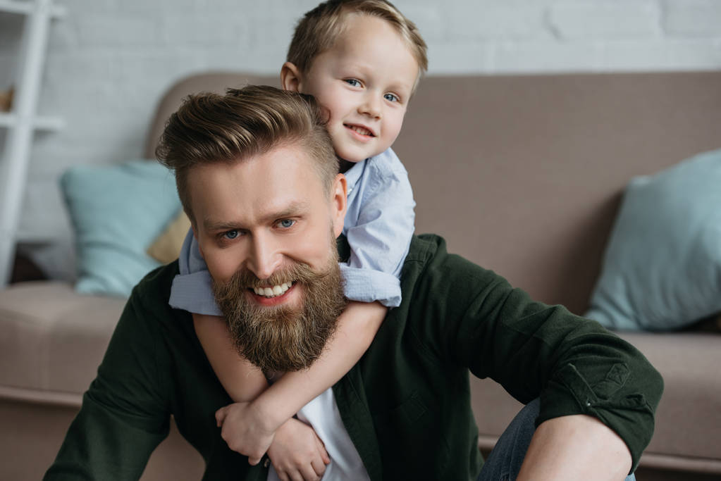 портрет маленького сына, обнимающего улыбающегося бородатого отца дома
 - Фото, изображение