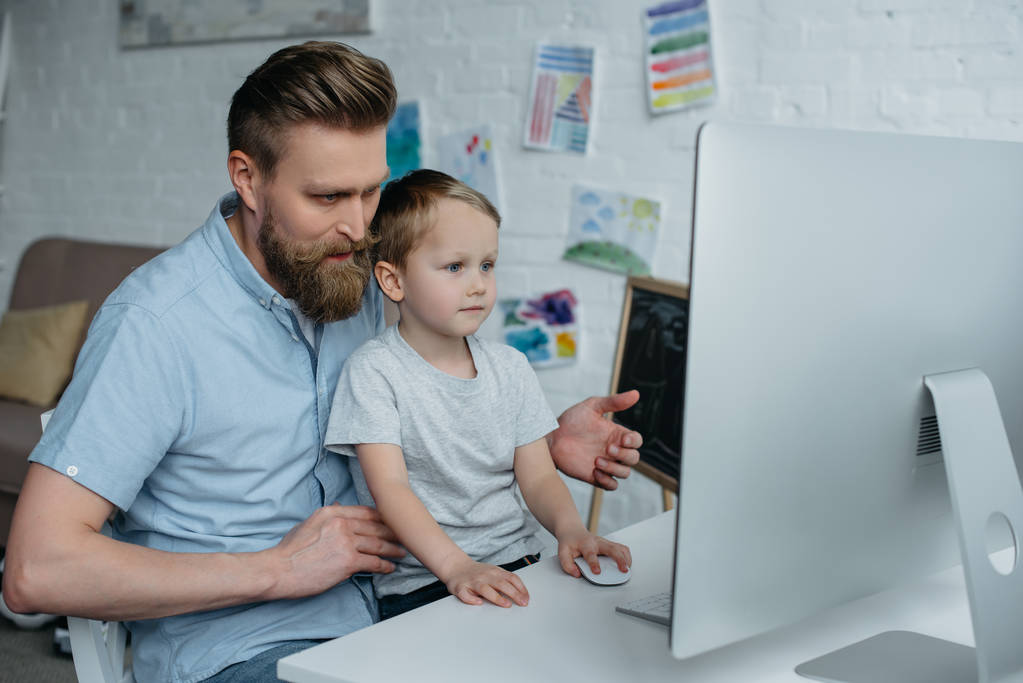 otec a malý syn při pohledu na obrazovku počítače při používání počítače u vás doma - Fotografie, Obrázek