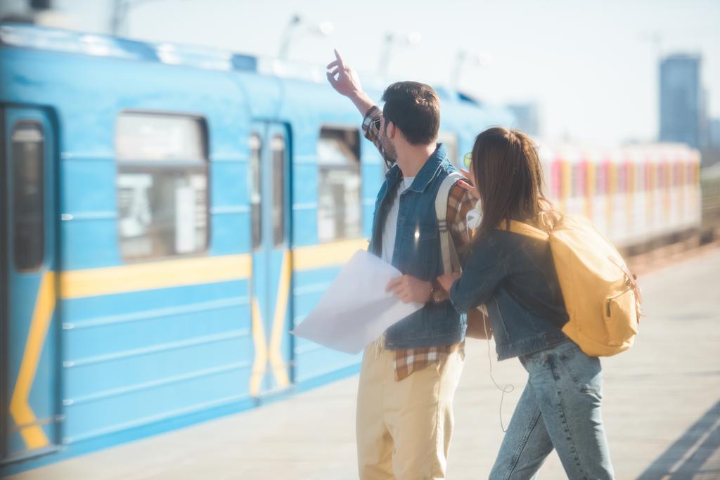 stijlvolle mannelijke tourist met arm aan de orde gesteld en vriendin op buiten metrostation  - Foto, afbeelding