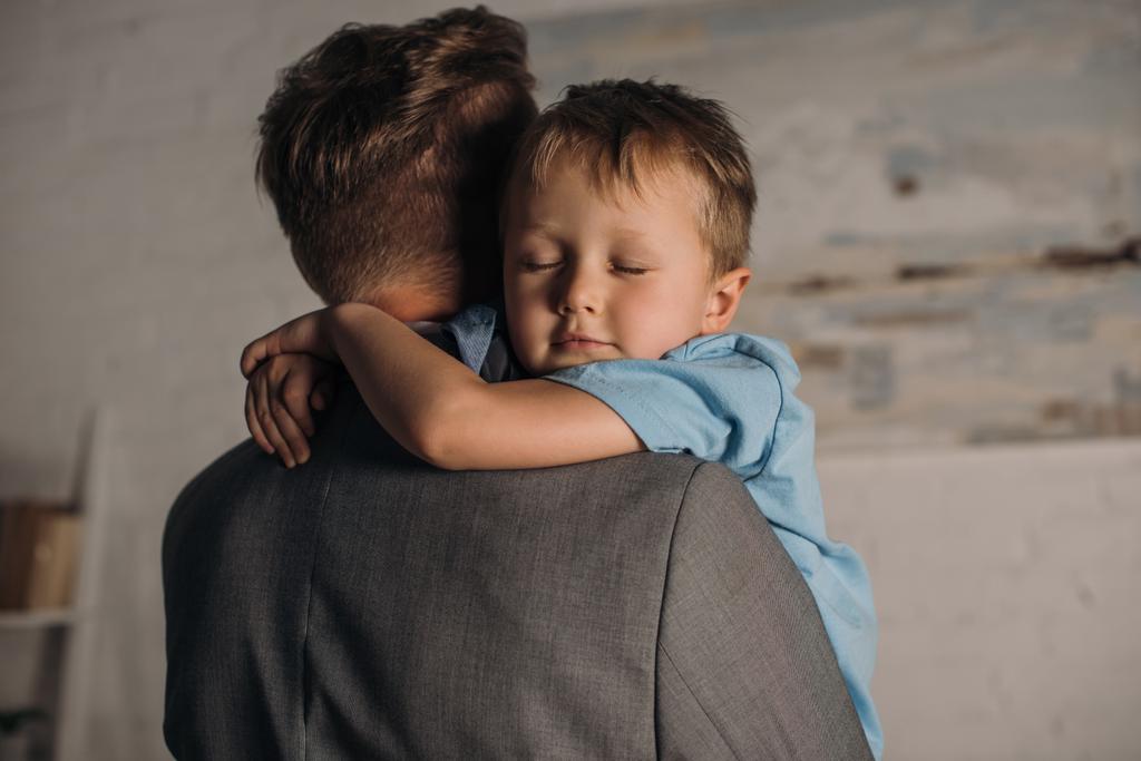 menino com olhos fechados abraçando pai em casa
 - Foto, Imagem
