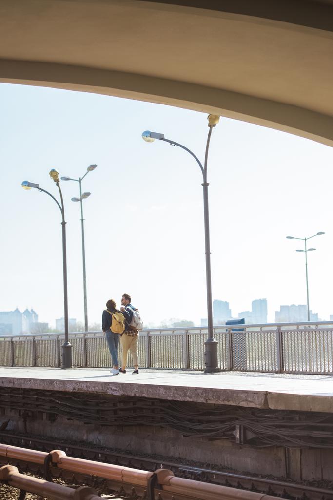 vista lejana de la elegante pareja de turistas que van en la estación de metro al aire libre
  - Foto, imagen