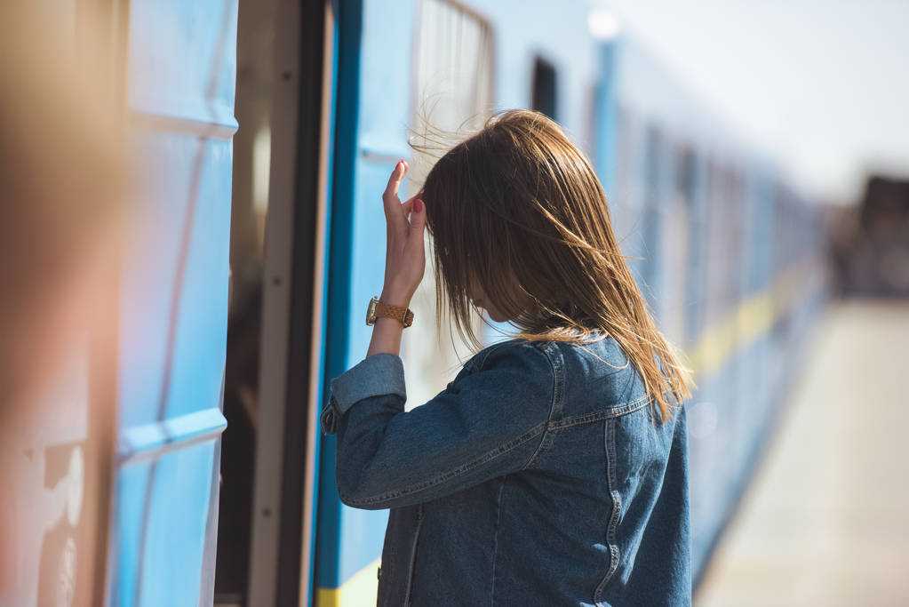 Widok z boku stylowe kobiety z zegarek na rękę, wchodząc w pociągu na stacji metra odkryty  - Zdjęcie, obraz