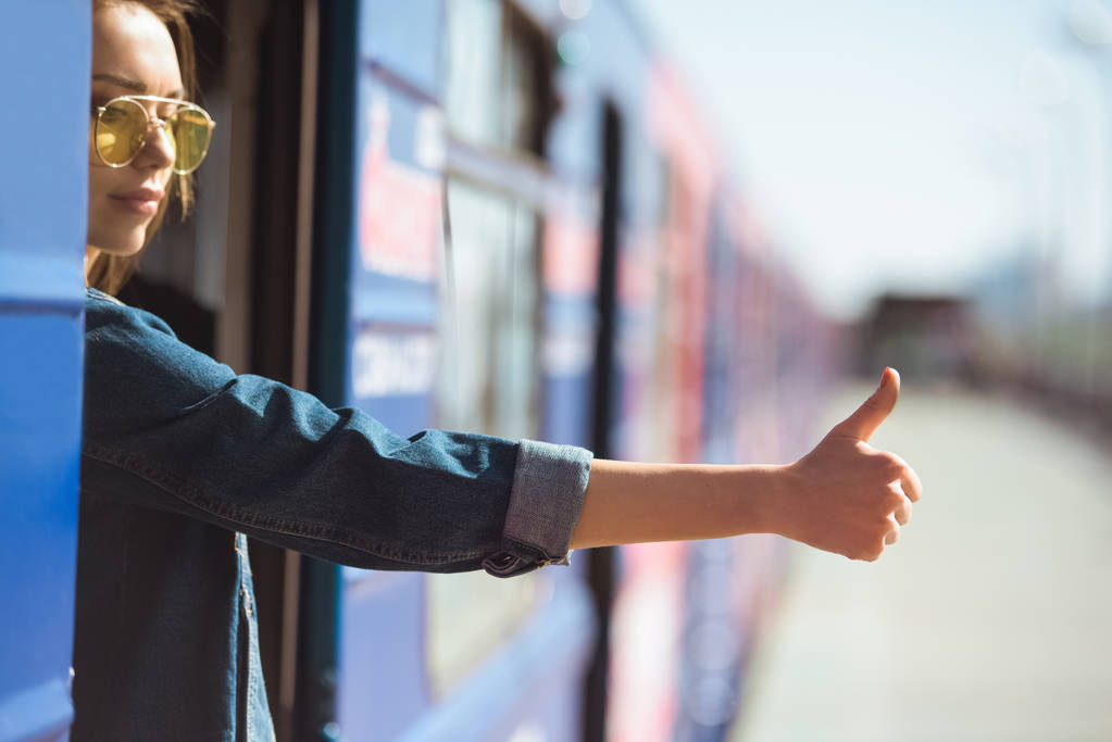 elegantní žena v sluneční brýle ve vlaku a na tom rána se gesto na venkovní stanice  - Fotografie, Obrázek