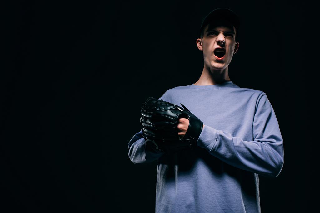 Кричащий молодой человек в бейсбольной перчатке, изолированный на черном
 - Фото, изображение