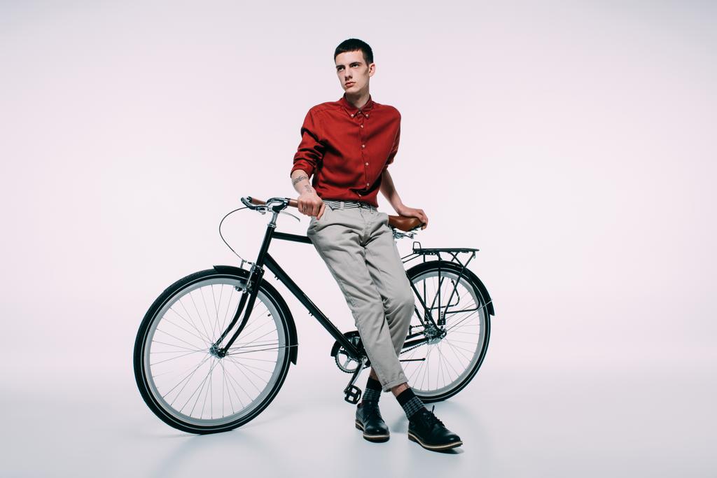 白い背景の上の彼の自転車にもたれて若い男 - 写真・画像