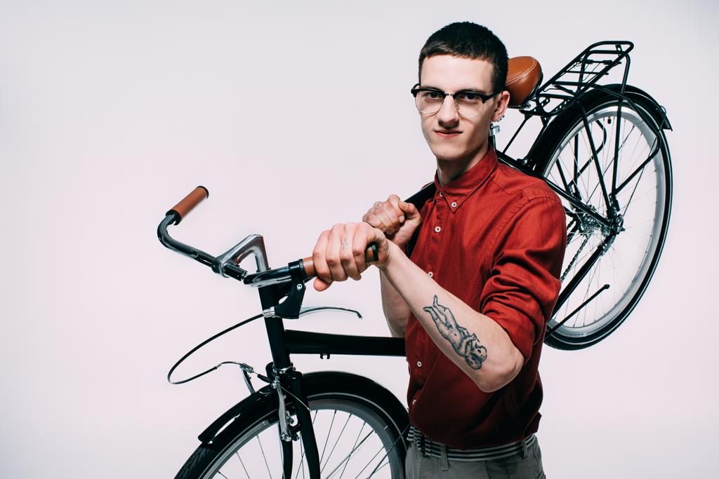 Fiatal férfi szemüveg gazdaság vállára elszigetelt fehér biciklivel - Fotó, kép