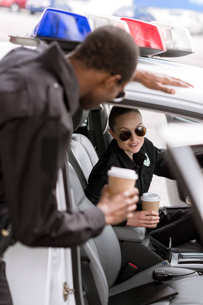 Молодые полицейские с машиной пьют кофе, чтобы пойти
 - Фото, изображение