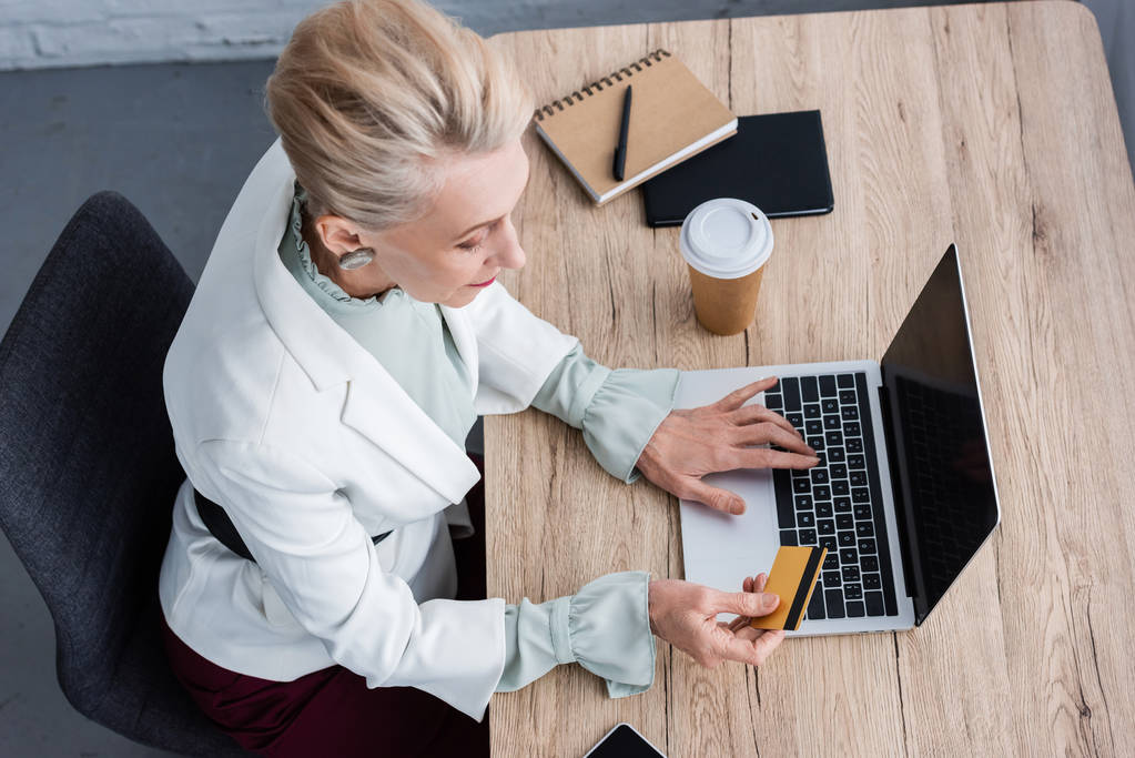 vue aérienne d'une femme d'affaires élégante utilisant un ordinateur portable et une carte de crédit sur le lieu de travail
 - Photo, image