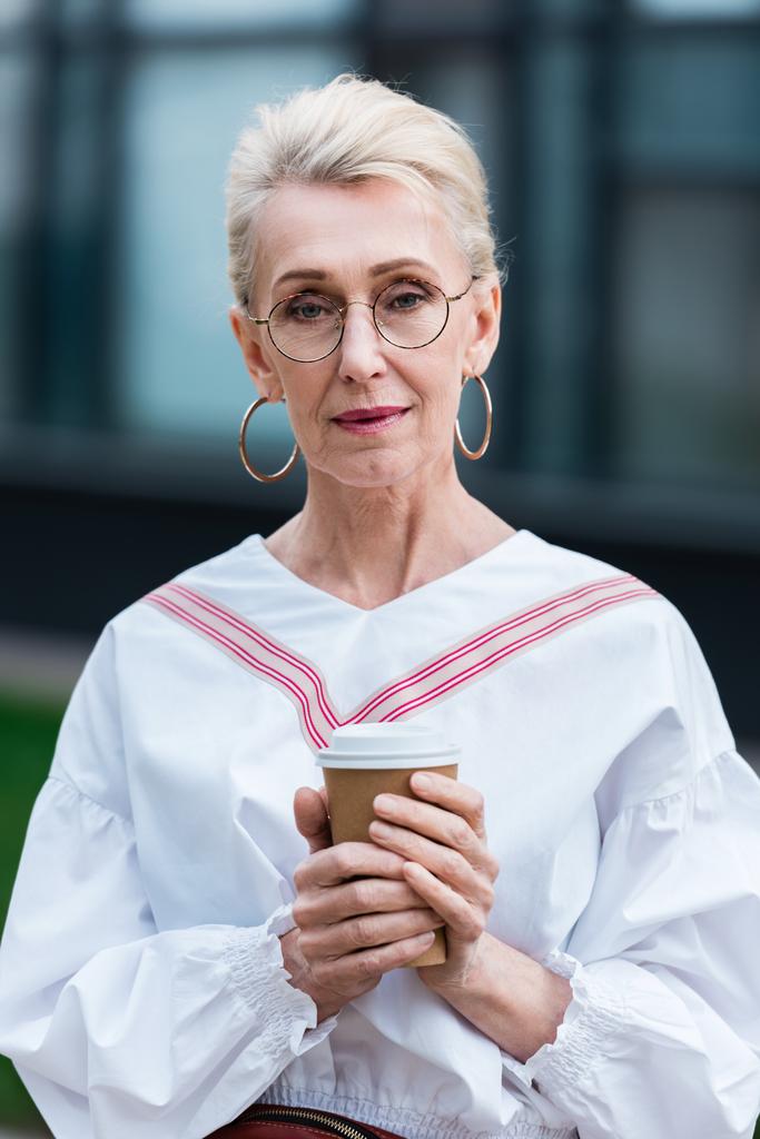 attraktive, stylische Seniorin in trendiger Brille mit Coffee to go - Foto, Bild