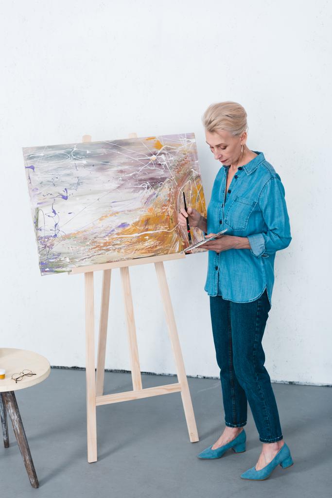 senior female artist painting in workshop - Photo, Image