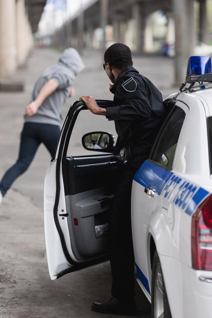 policía afroamericano saliendo del coche y persiguiendo al ladrón
 - Foto, imagen