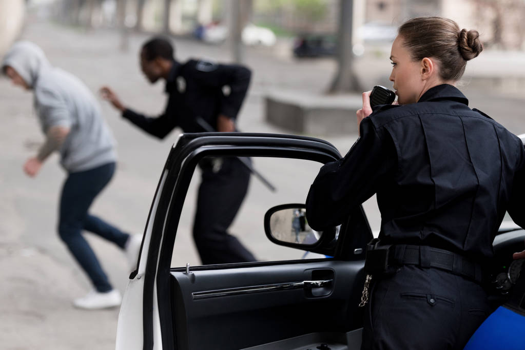 poliziotta parlando da radio set mentre il suo partner insegue ladro
 - Foto, immagini