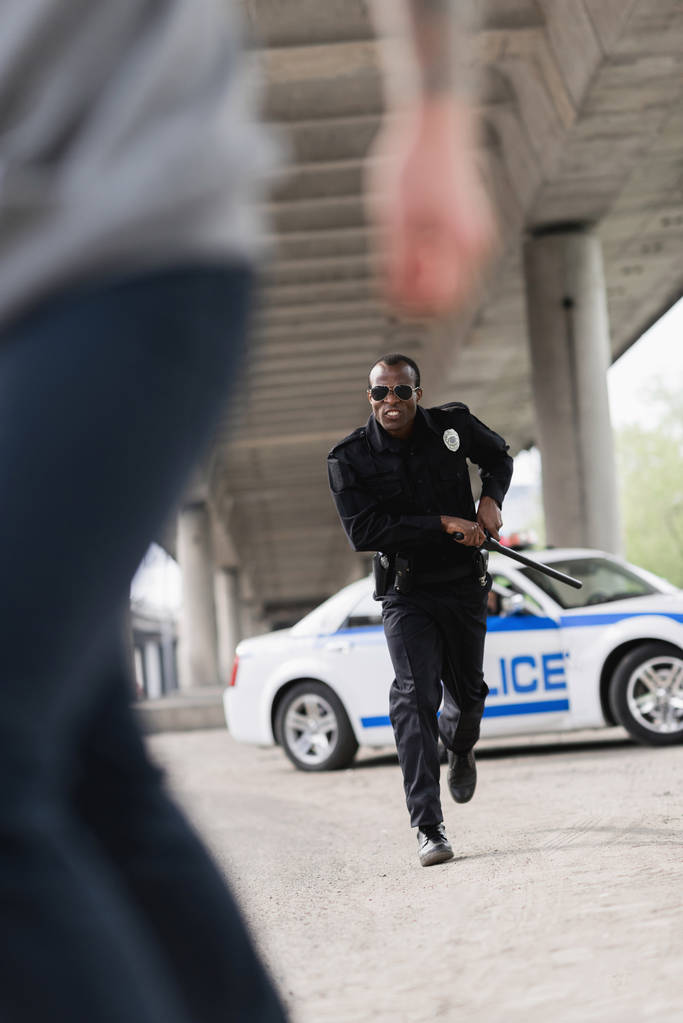 tiro cortado de ladrão correndo de policial afro-americano
 - Foto, Imagem