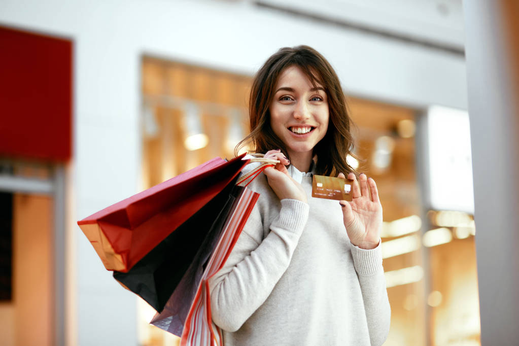 ショッピング モールで買い物袋を持つクレジット カード女性. - 写真・画像