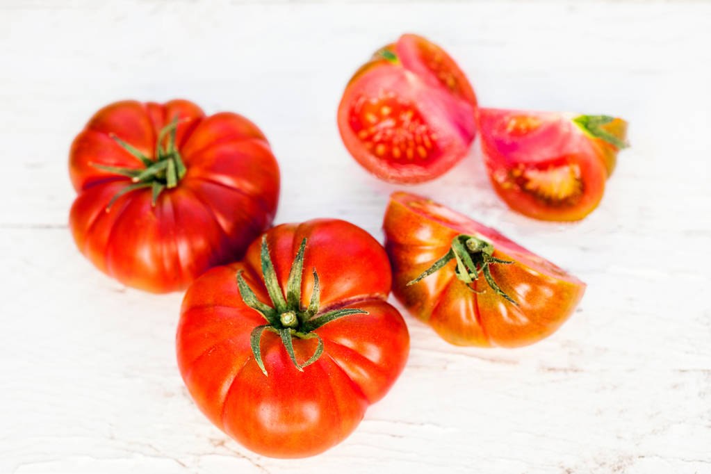 całe lub posiekane świeże dojrzałe pomidory na jasnym tle drewnianych - Zdjęcie, obraz