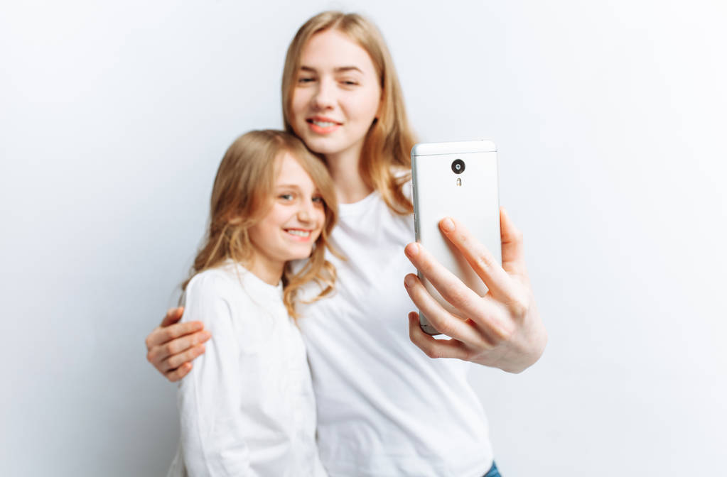 Mutter oder ältere Schwester macht Selfie kleines Mädchen, glückliche Familie, Fotostudio, isoliert - Foto, Bild
