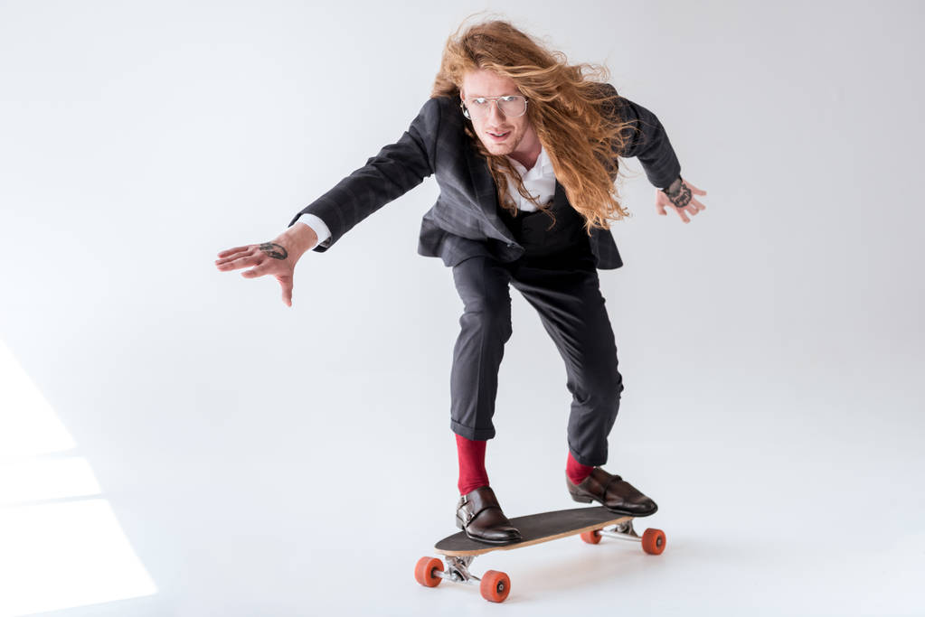 stylish businessman with curly hair skating on longboard  - Photo, Image