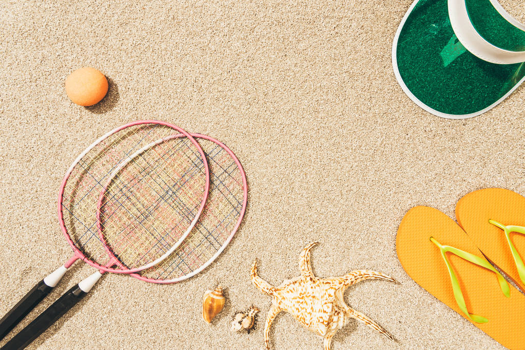 vue de dessus de l'équipement de badminton, capuchon et tongs sur sable
 - Photo, image