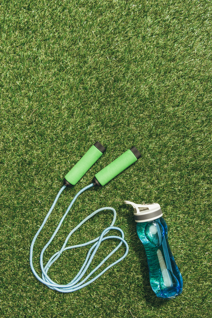 top view of arranged water bottle and skipping rope on green grass - Photo, Image