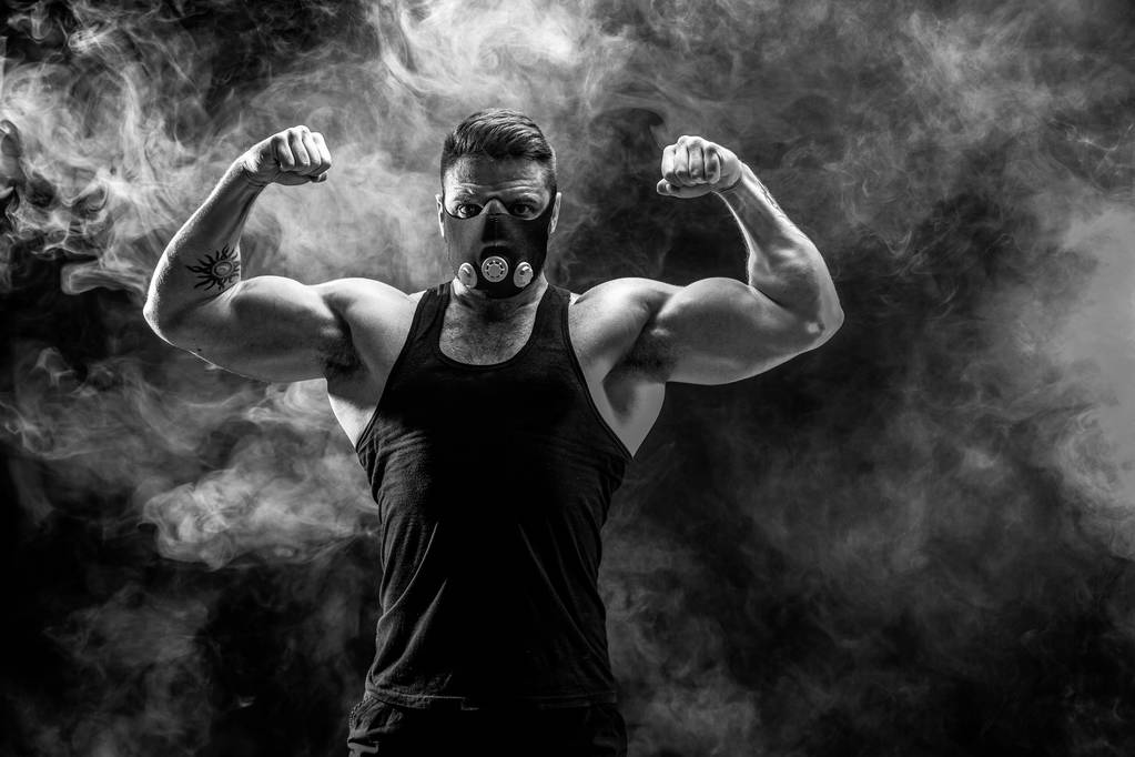 Silny mężczyzna sportowiec w maskę szkolenia czarne na czarnym tle - Zdjęcie, obraz