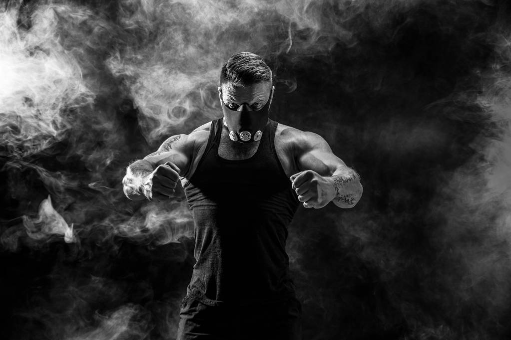 Fuerte atleta masculino en una máscara de entrenamiento negro sobre un fondo negro
 - Foto, imagen