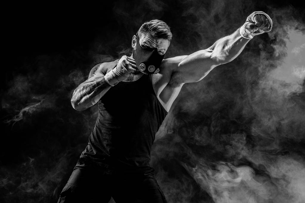 Fuerte atleta masculino en una máscara de entrenamiento negro sobre un fondo negro
 - Foto, Imagen