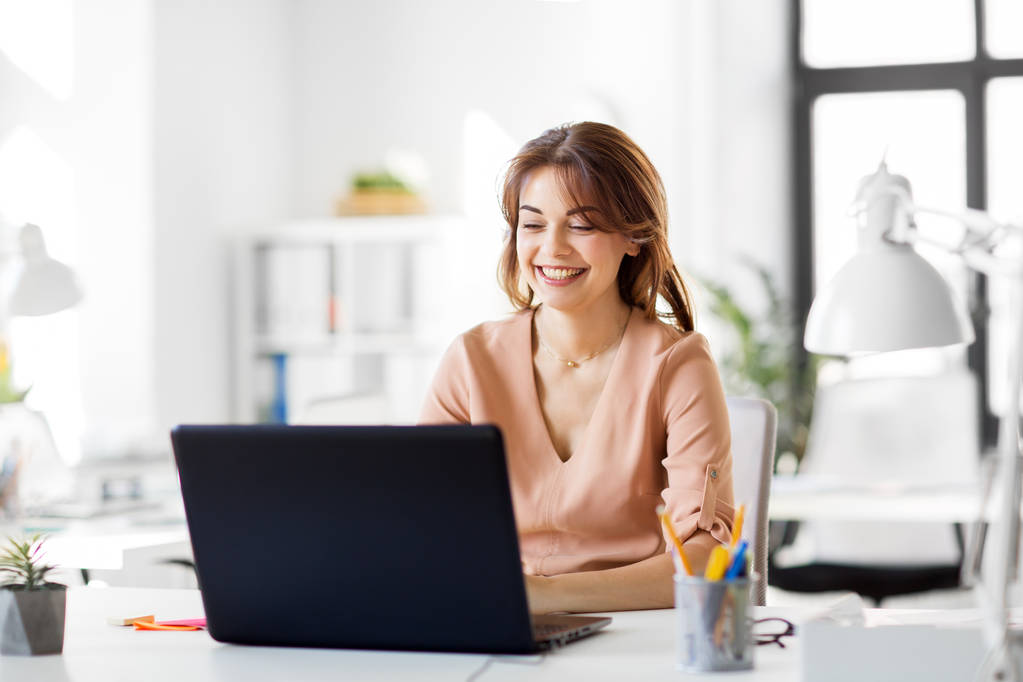 szczęśliwa bizneswoman z laptopem pracująca w biurze - Zdjęcie, obraz