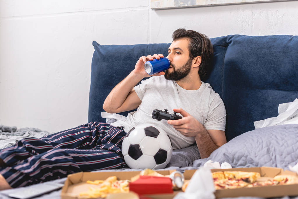 ビデオ ゲームをプレイし、寝室で飲み物を飲む男性の孤独 - 写真・画像