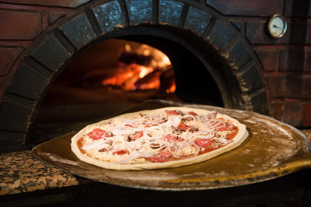 close up view of cooking process of raw pizza on wooden stove in brick oven - Photo, Image