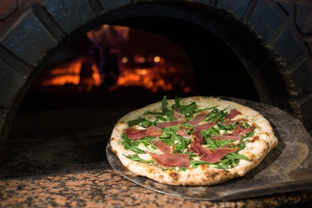 Zobacz proces raw pizza na drewniany piec w brick piec do gotowania z bliska - Zdjęcie, obraz