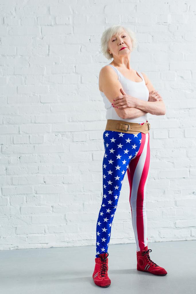 mulher sênior confiante em sportswear de pé com braços cruzados e olhando para a câmera
 - Foto, Imagem
