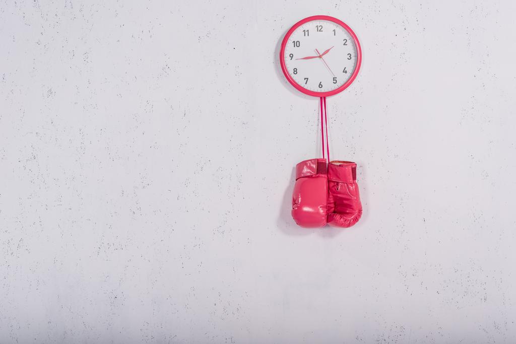 pink boxing gloves hanging at wall clock on white - Photo, Image