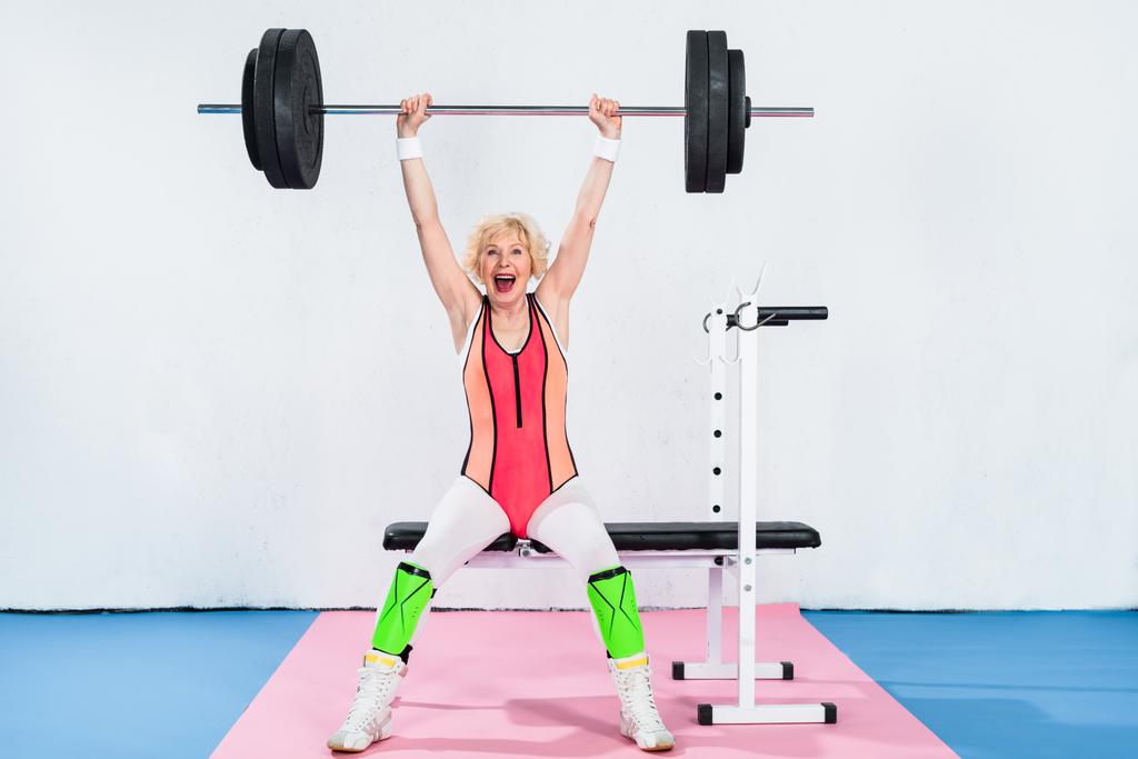 excited senior sportswoman lifting barbell - Photo, Image