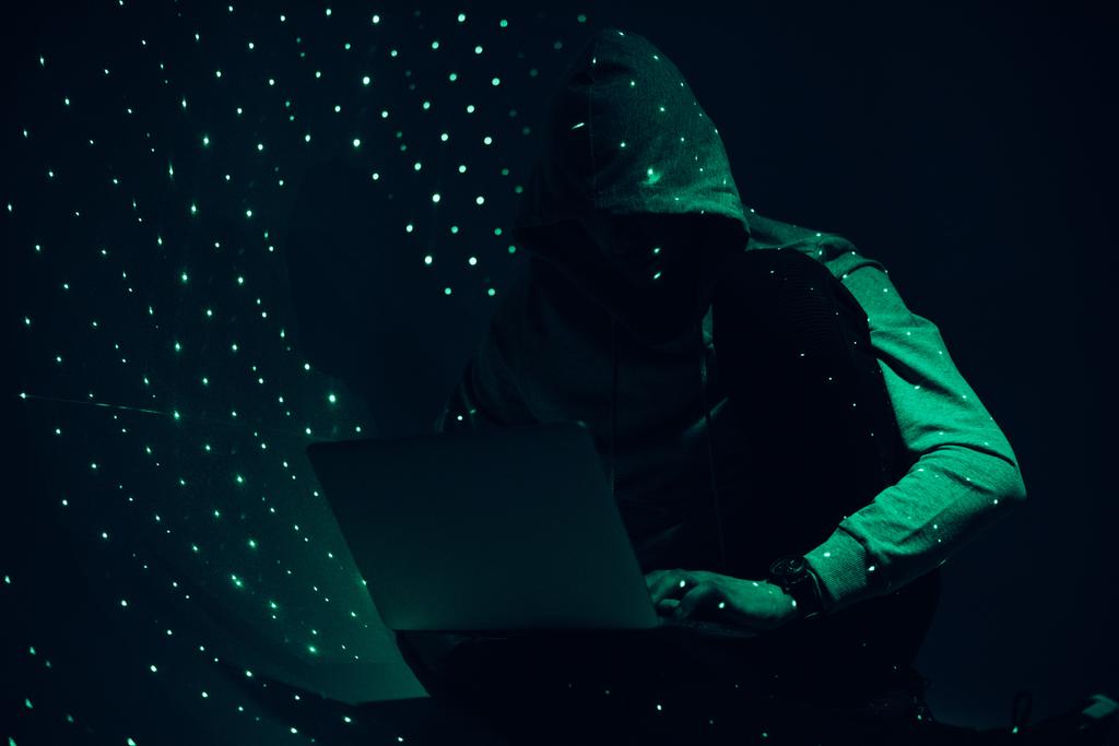 тонированное изображение силуэта хакера в толстовке с помощью ноутбука
 - Фото, изображение