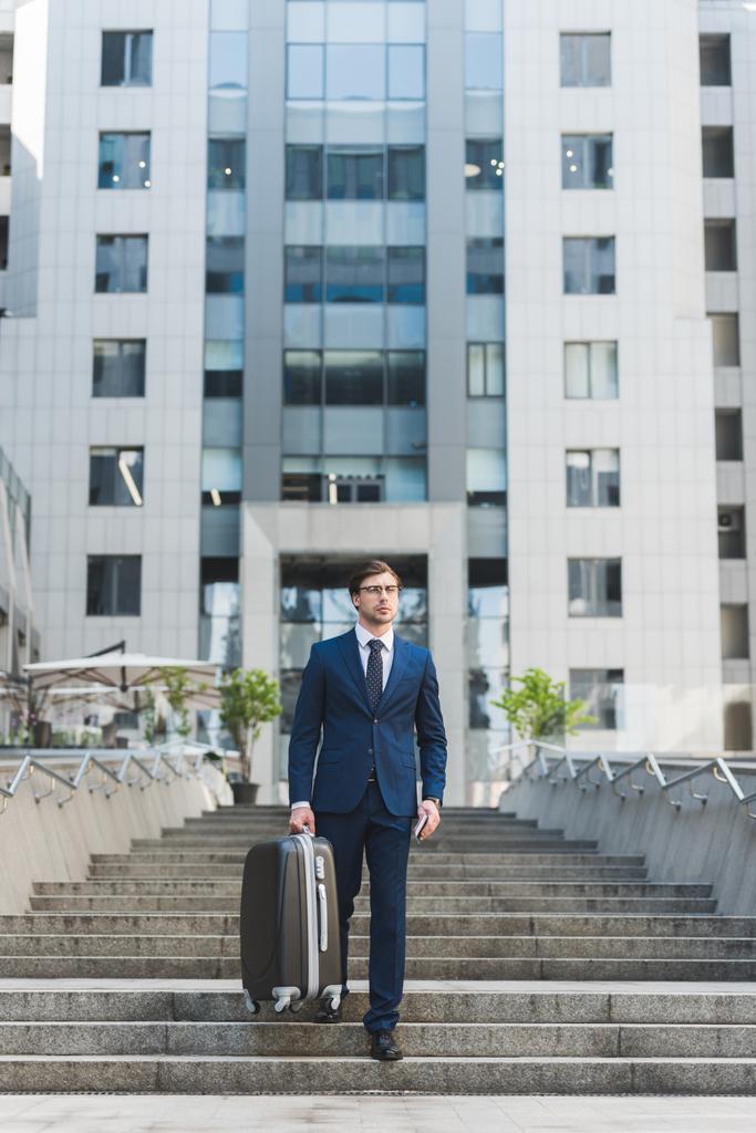 joven hombre de negocios con estilo con equipaje caminando por el distrito de negocios
 - Foto, Imagen