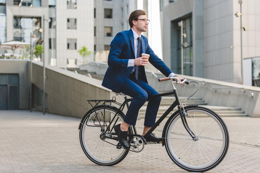 ヴィンテージ自転車に座って行くのコーヒーでスタイリッシュなスーツの青年実業家 - 写真・画像