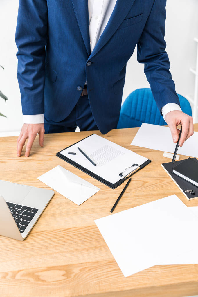vue partielle de l'homme d'affaires sur le lieu de travail avec des ordinateurs portables, bloc-notes et ordinateur portable dans le bureau
 - Photo, image