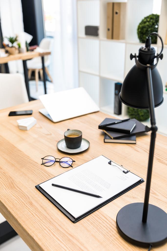 primer plano vista de la taza de café, anteojos, documentos y lámpara en el lugar de trabajo en la oficina
 - Foto, imagen